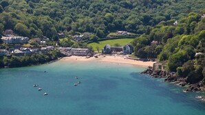 Un pueblo costero con una playa, barcos y casas.