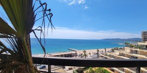 A balcony with a view of the sea, buildings, and a palm tree. - Apartment 3p with terrace on the seafront (Fréjus)