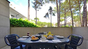 Una mesa redonda con sillas, platos de comida, vasos y una jarrón.