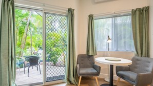 A room with two grey armchairs, a small round table, and a window with sheer curtains.