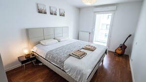 Un dormitorio con cama, una guitarra, una mesita de noche y una ventana.