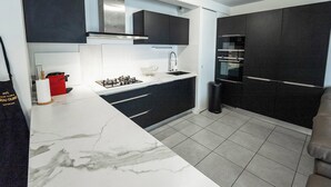 Una cocina moderna con armarios oscuros, una encimera blanca y un horno empotrado.