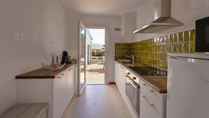 Eine schmale Küche mit weißen Schränken, einer Holz Arbeitsplatte und einer grünen Fliesen backsplash.