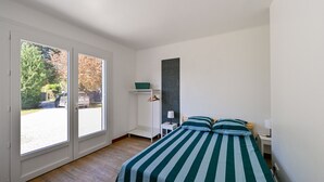 Ein Schlafzimmer mit einem Bett, einem Kleiderschrank, einem Schreibtisch und einem großen Fenster.