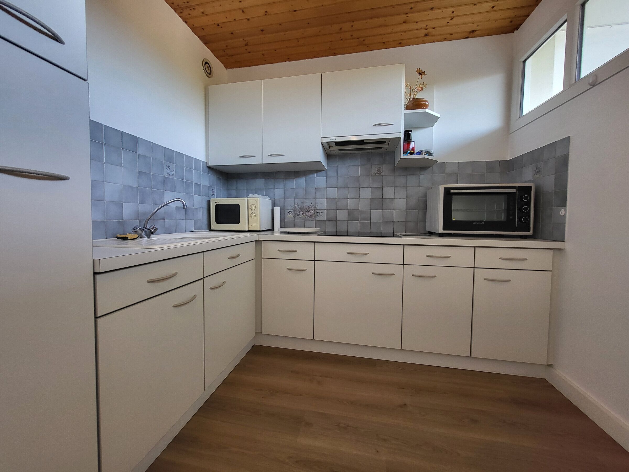 A kitchen with white cabinets, a microwave, a toaster, and a sink.