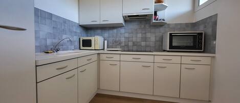 A kitchen with white cabinets, a microwave, a toaster, and a sink.