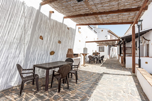 An outdoor patio with stone flooring, wooden tables, and chairs.