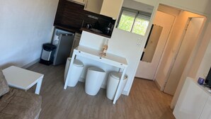 A compact kitchen with white cabinets, a refrigerator, and a small dining area with stools. - 1 bedroom apartment with balcony near the beach (Saint-Raphaël)