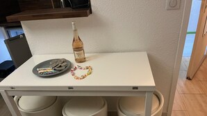 A small kitchen area with a white table, a bottle of wine, a plate with snacks, and two trash bins. - 1 bedroom apartment with balcony near the beach (Saint-Raphaël)