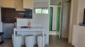 A compact kitchen with a white table, stools, and a wine bottle. - 1 bedroom apartment with balcony near the beach (Saint-Raphaël)