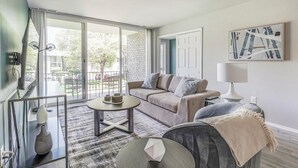 A modern living room with a sofa, coffee table, and a view of the outdoors.