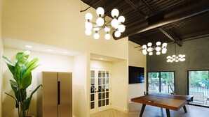 A spacious room with a large wooden table, a potted plant, and a modern chandelier. - Landing | Amazing Studio, Pool, Gym (Raleigh)