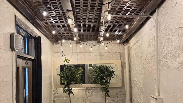 Un espacio interior acogedor con techo rústico, dos sillones, una mesita y una planta en maceta.