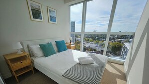 A bedroom with a large bed, a nightstand, a lamp, and two framed pictures on the wall.