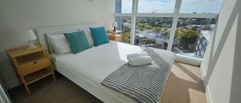 A bedroom with a large bed, a nightstand, a lamp, and two framed pictures on the wall.