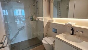 A modern bathroom with a glass shower enclosure, a white sink, and a large mirror.