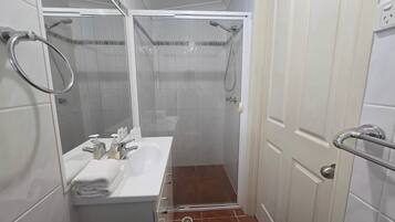 A small bathroom with a shower, a sink, and a toilet.