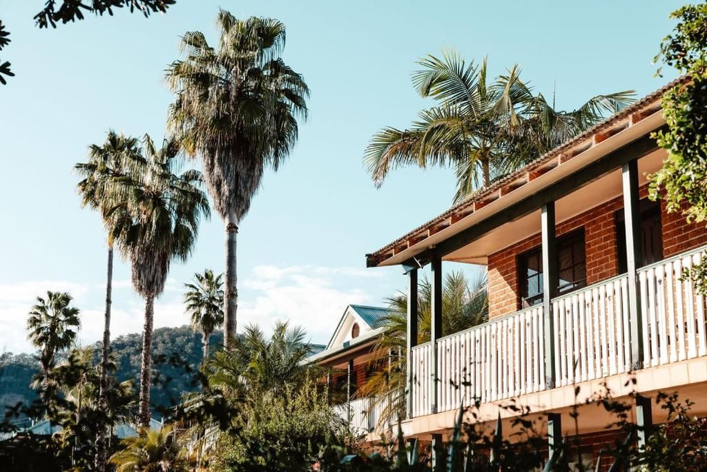 A two-story building with a balcony, surrounded by palm trees.
