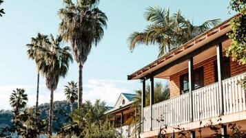 A two-story building with a balcony, surrounded by palm trees.