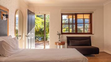 Relax in this serene bedroom with a large bed, a window offering a view of lush greenery, and a small table for reading.