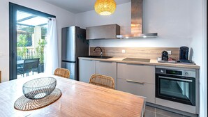 Une cuisine moderne équipée d’un four encastré, d’une machine à café et d’un coin repas avec une table et des chaises.