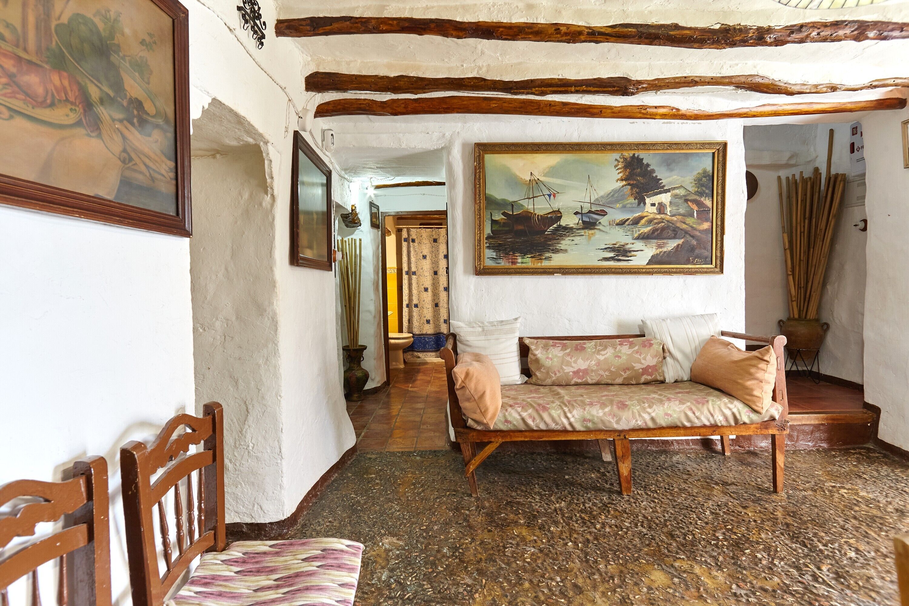Un interno rustico con un divano di legno, un quadro e un pavimento in maiolica tradizionale.
