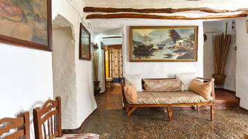 Un interno rustico con un divano di legno, un quadro e un pavimento in maiolica tradizionale.