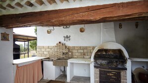 Een landelijke keuken met een bakoven, een spoelbak en een raam met uitzicht op een tuin.