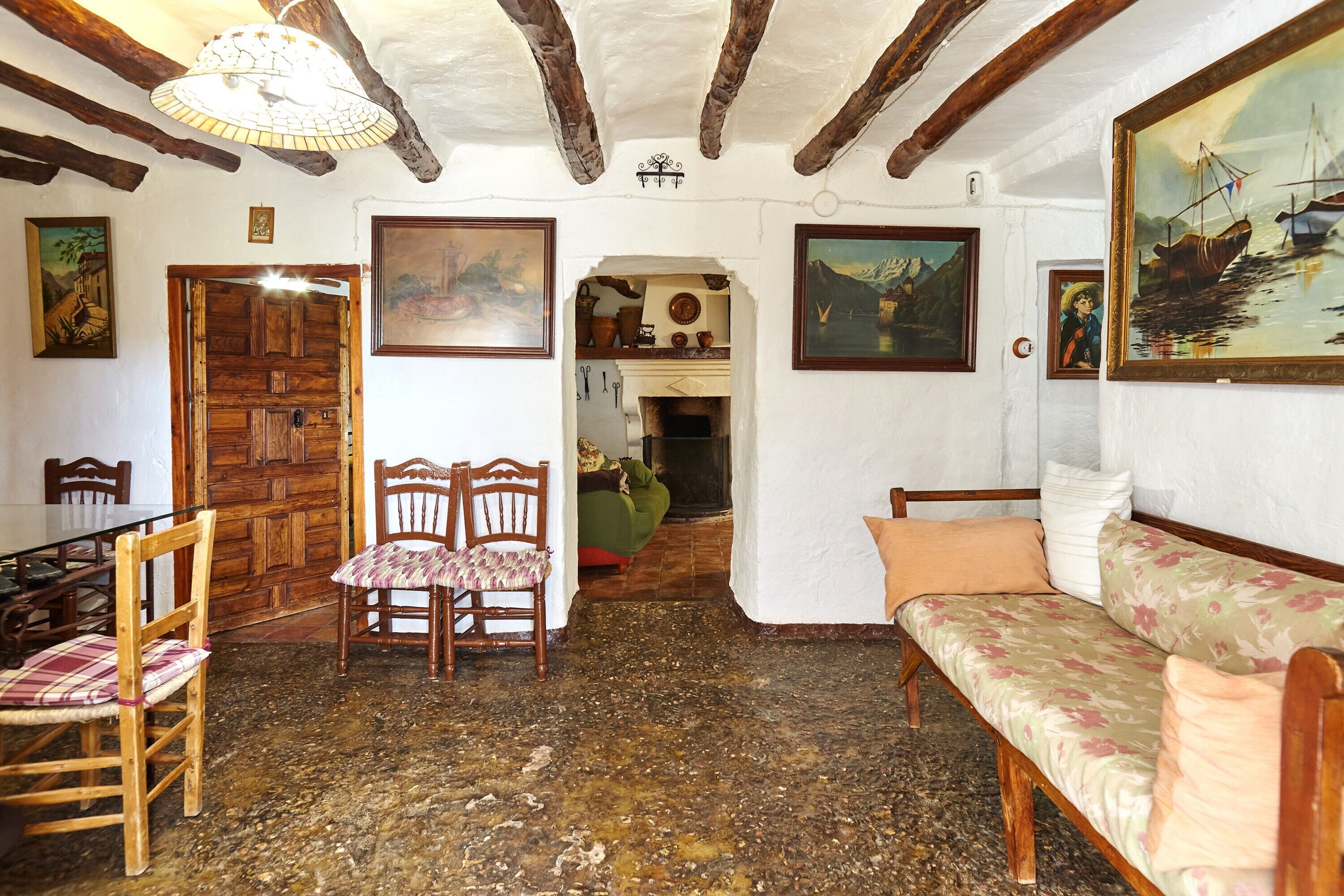 Ein rustikaler Innenraum mit einem Holzesstisch, Stühlen, einer Couch und Bildern an den Wänden.