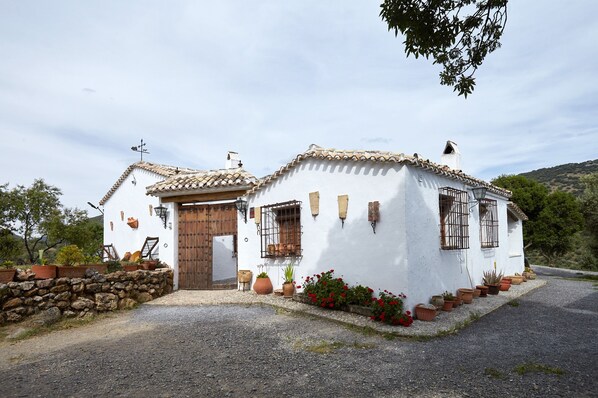 Un edificio blanco con techo de tejas, puerta de madera y pared de piedra.