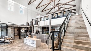 A spacious lobby with a herringbone floor, a reception desk, and a staircase leading to an upper level. - Sunny 2-Bed Oasis: Pool & Gym in Apollo Beach (Apollo Beach)