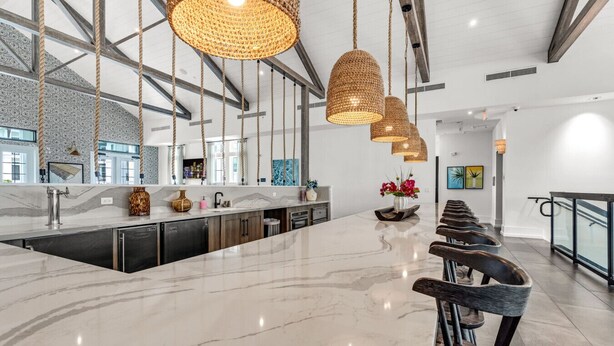 A modern kitchen with a marble countertop, hanging woven light fixtures, and a central island with seating. - Sunny 2-Bed Oasis: Pool & Gym in Apollo Beach (Apollo Beach)