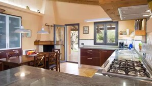 A modern kitchen with a central island, wooden cabinets, and a gas stove.