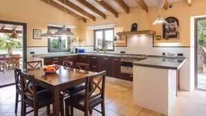 A modern kitchen with wooden beams, a central island, and a dining area with a table and chairs.