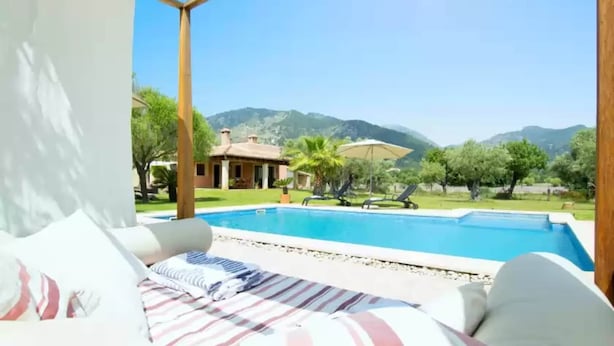 A bedroom with a view of a swimming pool and mountains.