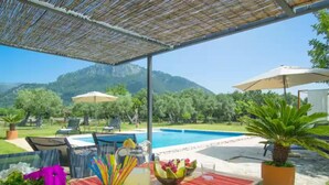 A poolside area with a table set for two, a drink, and fruit.