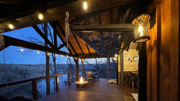 Une terrasse en bois avec un foyer, des sièges d’extérieur et un luminaire suspendu.