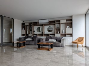 Ein modernes Wohnzimmer mit einer Sofagarnitur, zwei Couchtischen und einem Sessel.