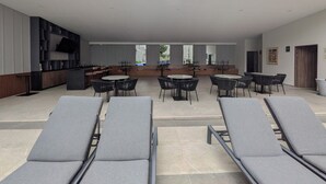 Eine Dachterrasse mit Liegestühlen und Tischen, einem Küchenbereich und Blick auf die Stadt.