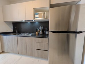 Una cocina moderna con un refrigerador de acero inoxidable, un microondas y una estufa a gas.