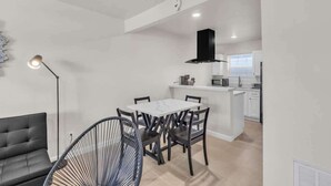 Een ruimtelijk ingerichte leefruimte met een eethoek, kitchenette en een bank.