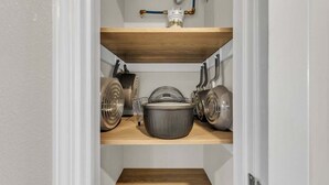 Een keuken met drie houten planken, een pan op de middelste plank en een waterkoker op de rechter plank.