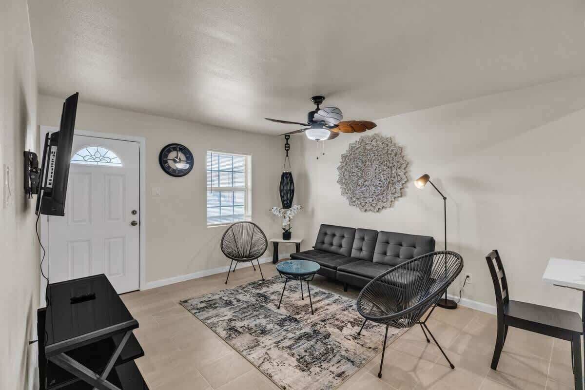 Un salon comprenant un canapé, des fauteuils, une table basse, un téléviseur et un ventilateur de plafond.