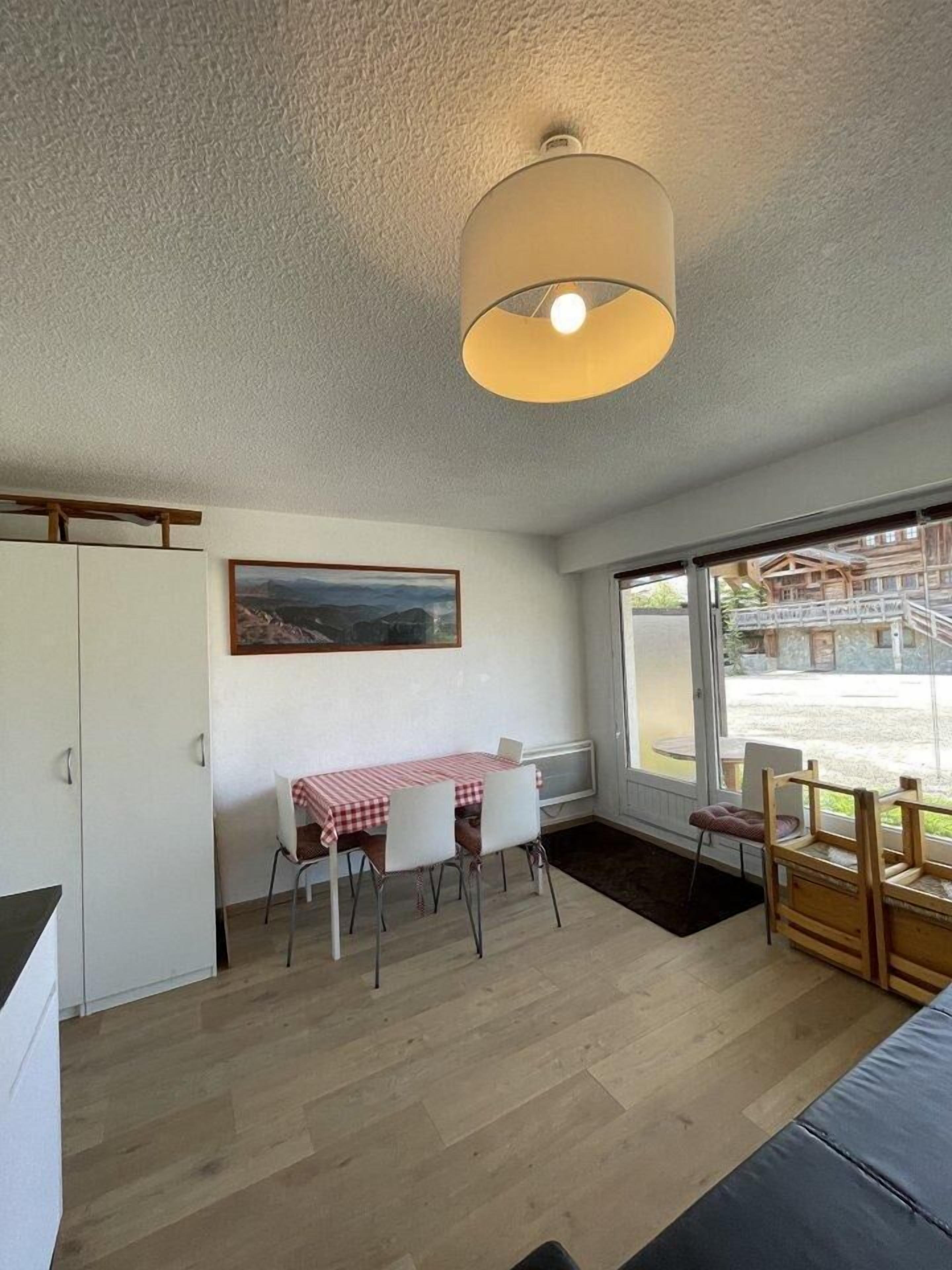 A dining area with a table and chairs, a painting on the wall, and a view of a building outside.