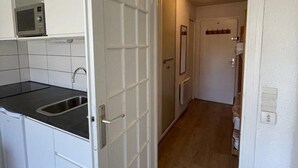 A kitchen with white cabinets, a black countertop, and a stainless steel sink. - 350m from ski slopes, Ground floor, terrace, tv, 24m², Alpe d'Huez (L'Alpe d'Huez)