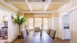 A dining room with a large wooden table, chairs, a potted plant, and a view of the kitchen through a window with blinds. - 2BR/1BA • Remodeled Duplex • Heart of Hawthorne (Portland)