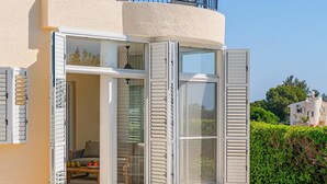 Una casa moderna con piscina, un balcón con barandilla y un ventanal corredero que da a una zona de estar exterior.