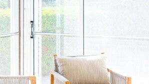 Una habitación luminosa con una mesa de madera, dos sillas acolchadas y un cuenco con fruta y jugo.