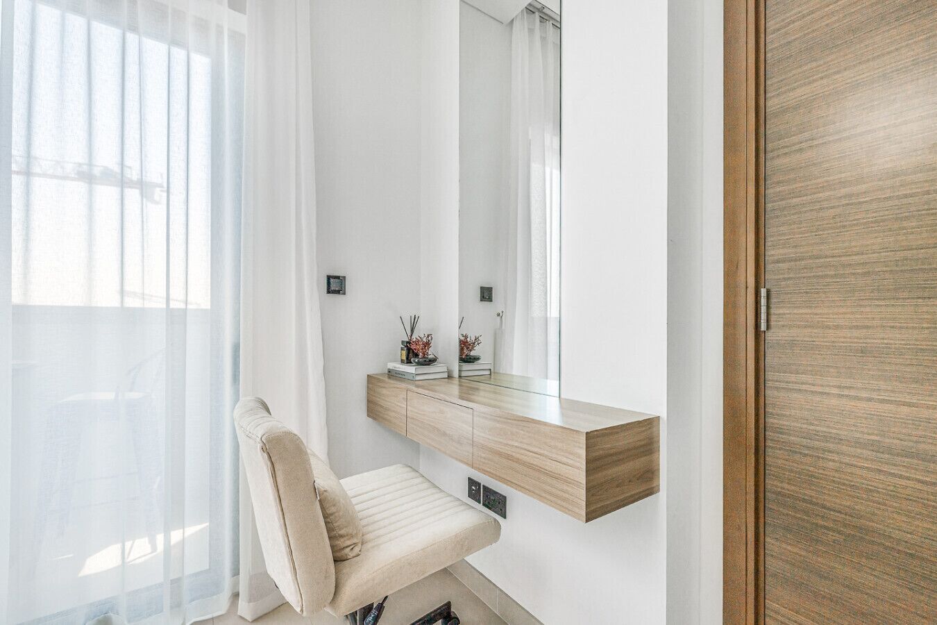 Een moderne badkamer met een houten wastafelmeubel, een spiegel en een stoel.