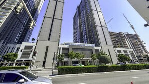 A modern building with a prominent vertical structure and a sign reading "SOBHA." - New 2BR with Pool & Gym in Green Sobha Community (Dubai)